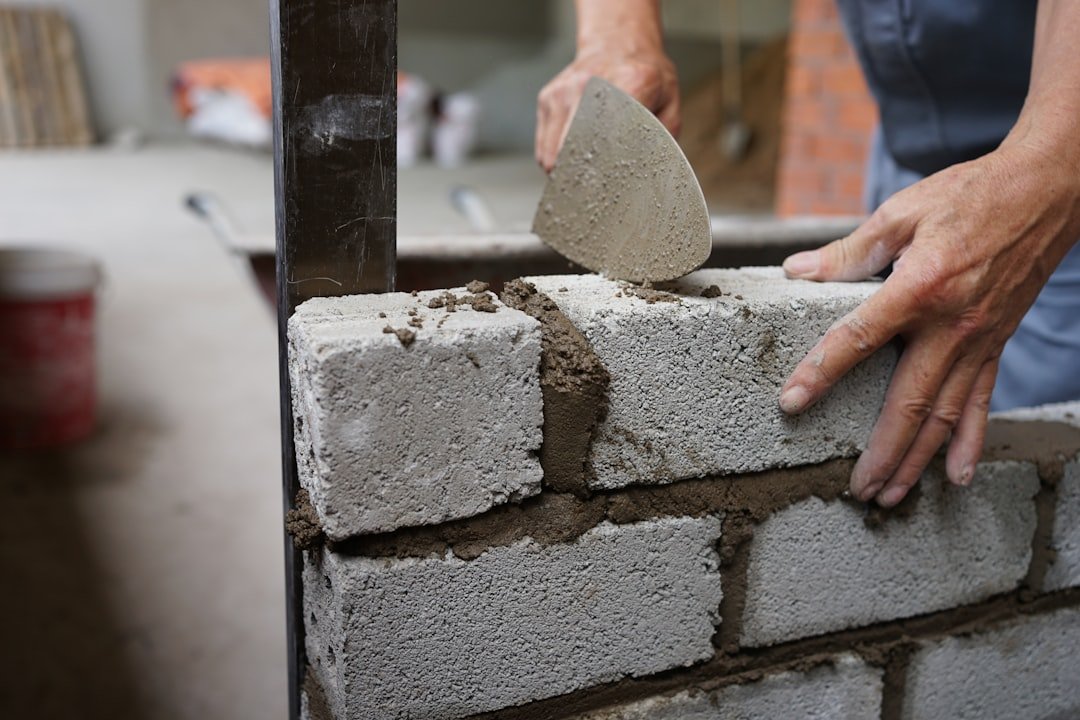 a-person-is-putting-cement-on-a-brick-wall-i6v6diaf71a
